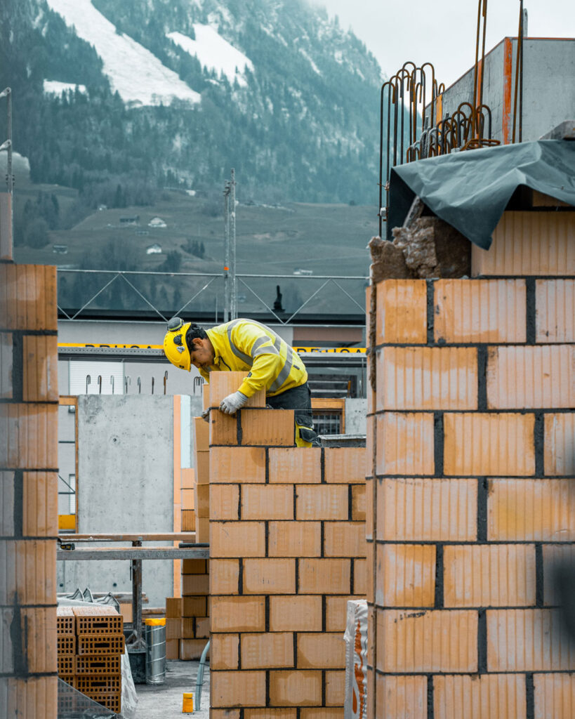 Ein Maurer arbeitet an einer Backsteinmauer