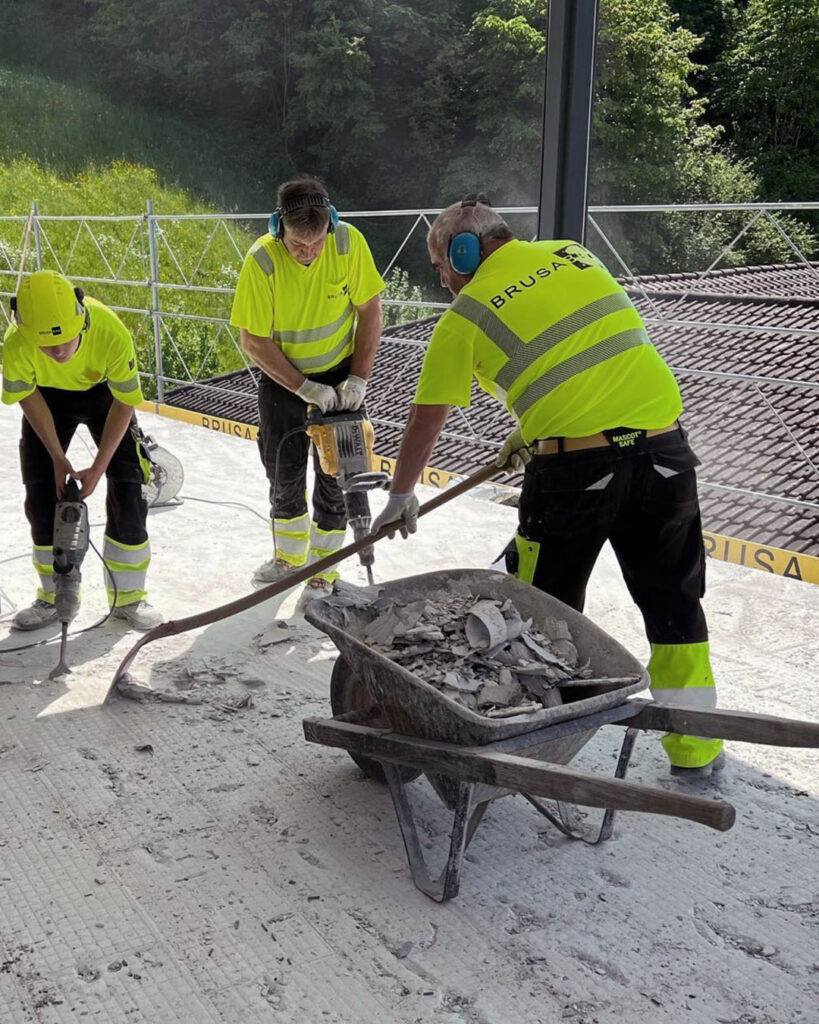 Drei Bauarbeiter entfernen den Bodenbelag eines Balkons