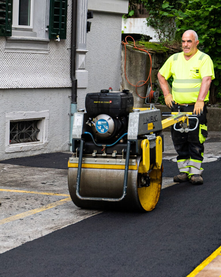 Arbeiter mit Strassenwalze auf frisch asphaltiertem Belag