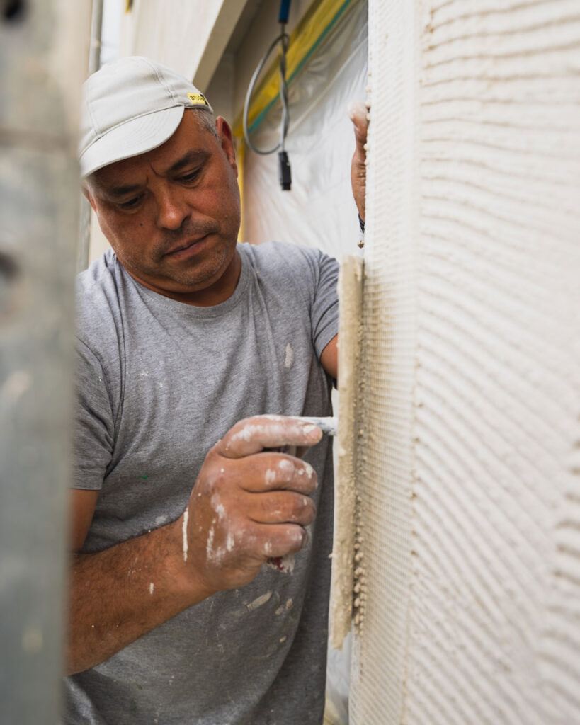 Ein Gipser macht einen Abrieb bei einer Aussenfassade.