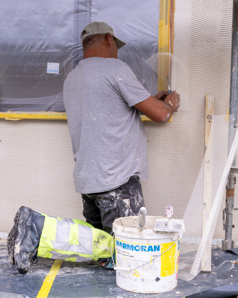 Ein Gipser arbeitet an einem Fensterdetail.