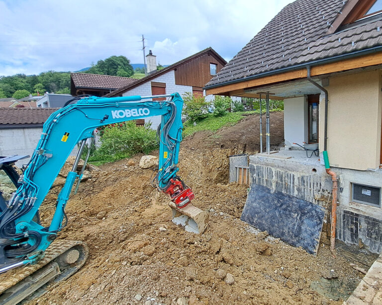 Aushubarbeiten mit Bagger vor einem zu renovierendem Einfamilienhaus.