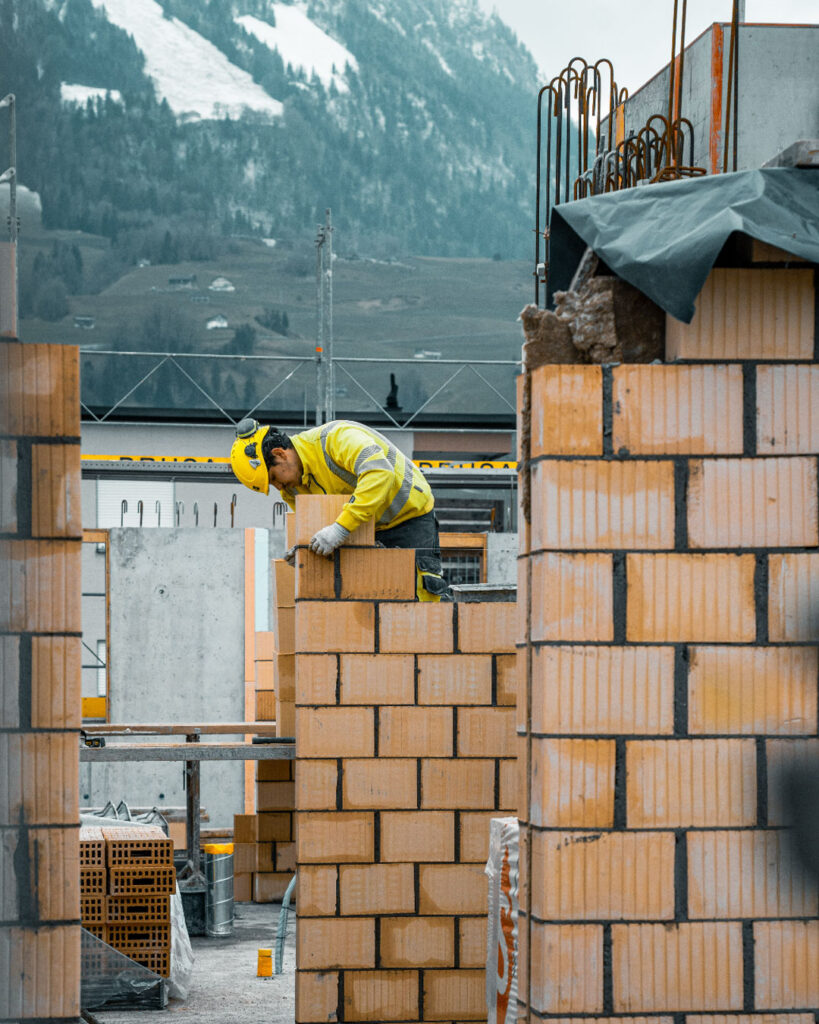 Ein Maurer arbeitet an einer Backsteinmauer.